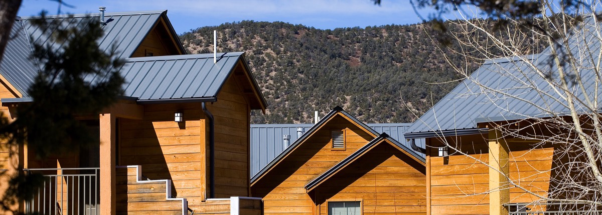 Wide view of wood-clad rooflines at Ladera against a pine-covered mountainside in Ruidoso Downs