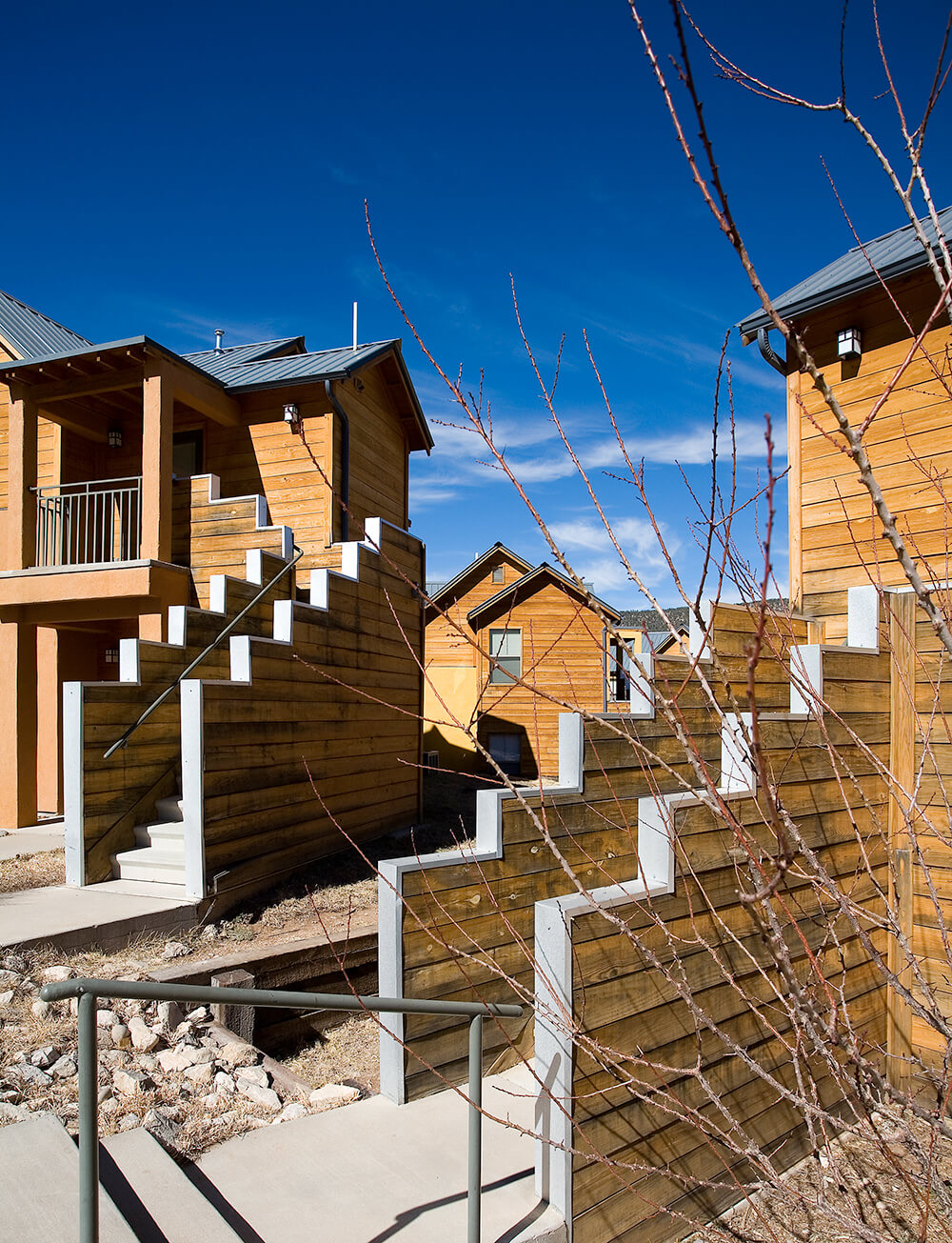 Concrete stairs and stepped timber walls between apartment homes at Ladera under a deep blue sky