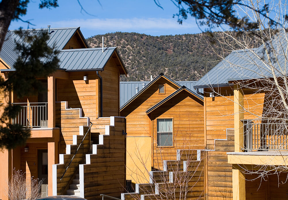 Apartment homes with wood siding and steel roofs climbing the hillside at Ladera, Ruidoso Downs NM